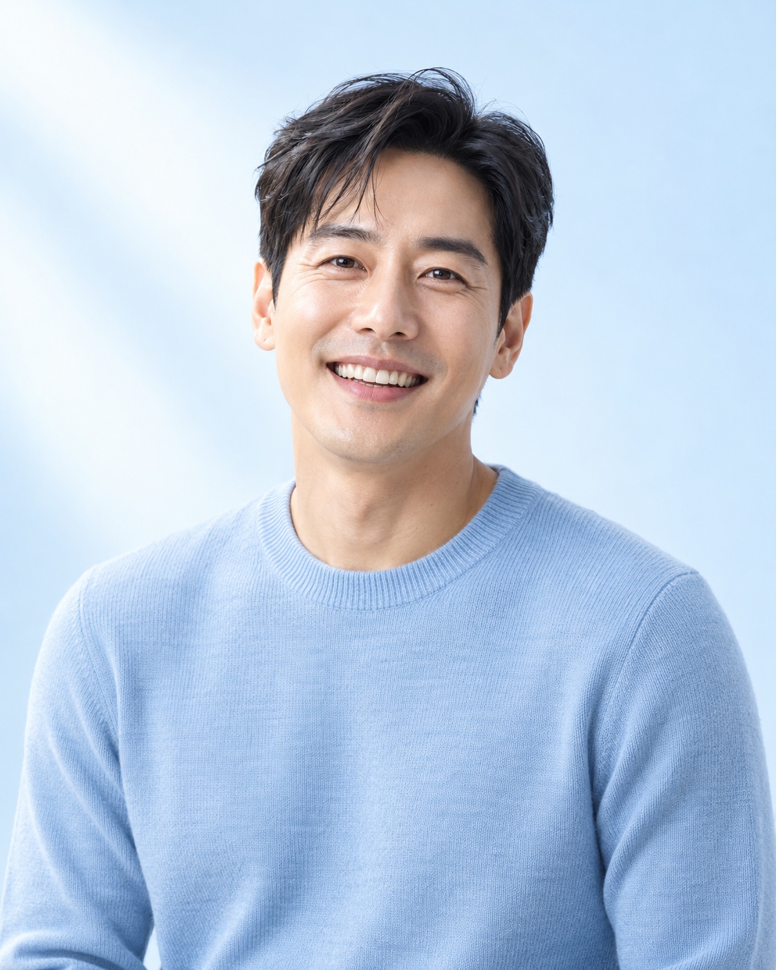 파우더블루 니트 차림으로 자연스럽게 미소 짓는 한국인 남성 모델